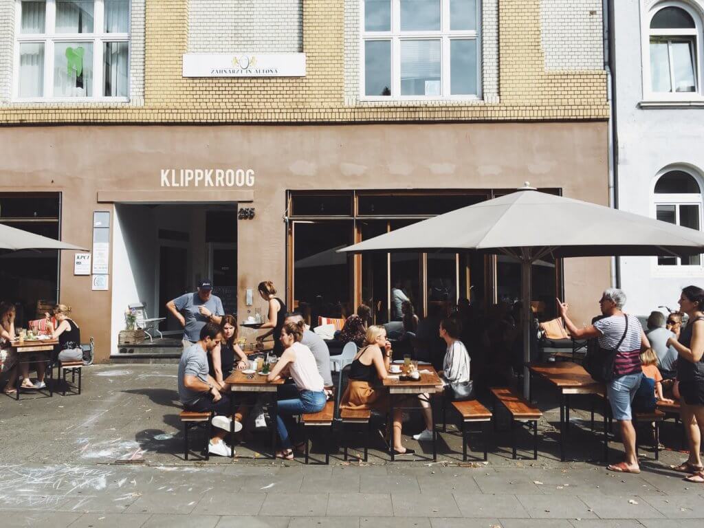 Customers enjoying outdoor dining at a sustainable cafe, embracing eco-friendly practices