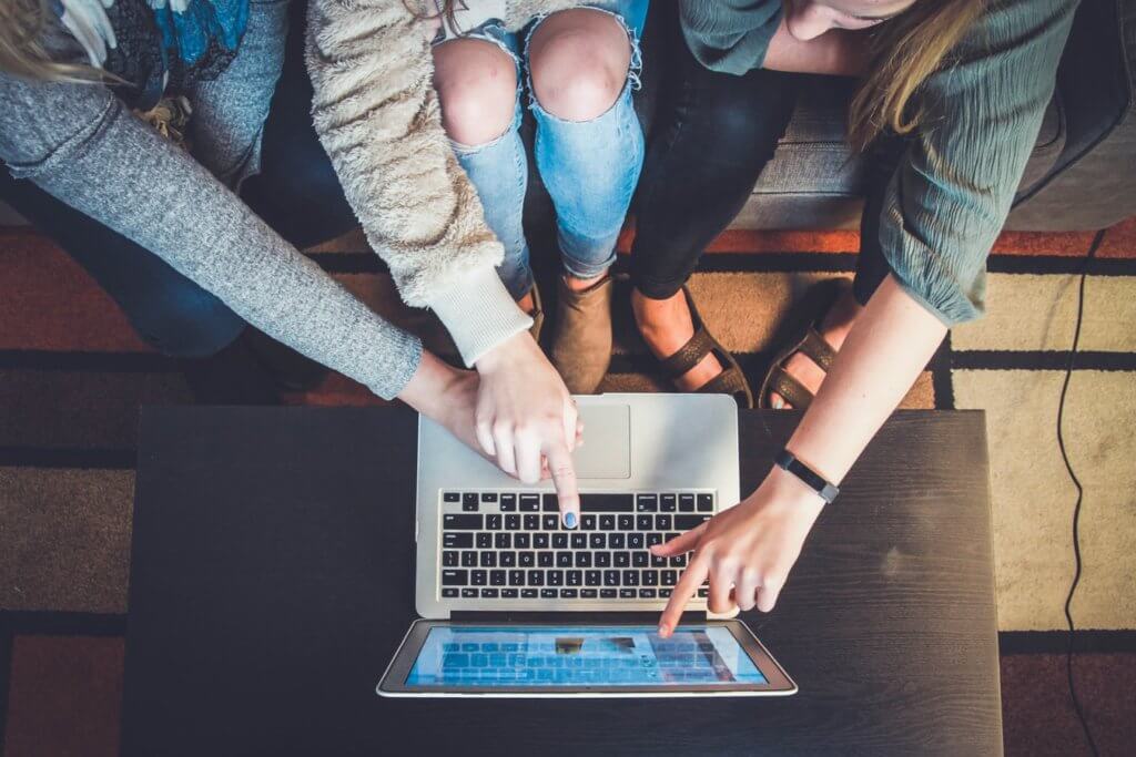 3 people looking and pointing at a laptop screen