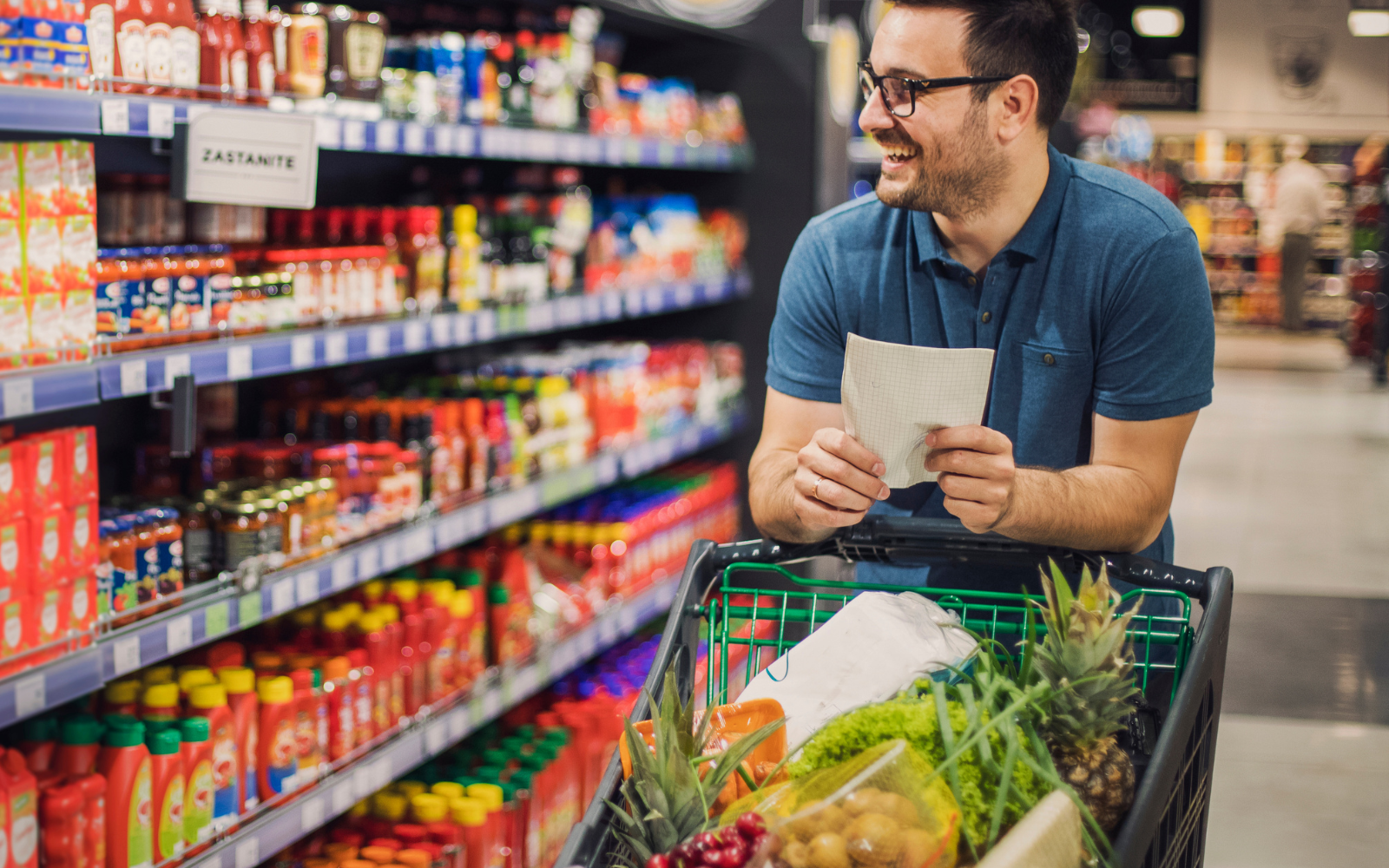 Image from Canva. Man shopping at a grocery store with a shopping cart.
