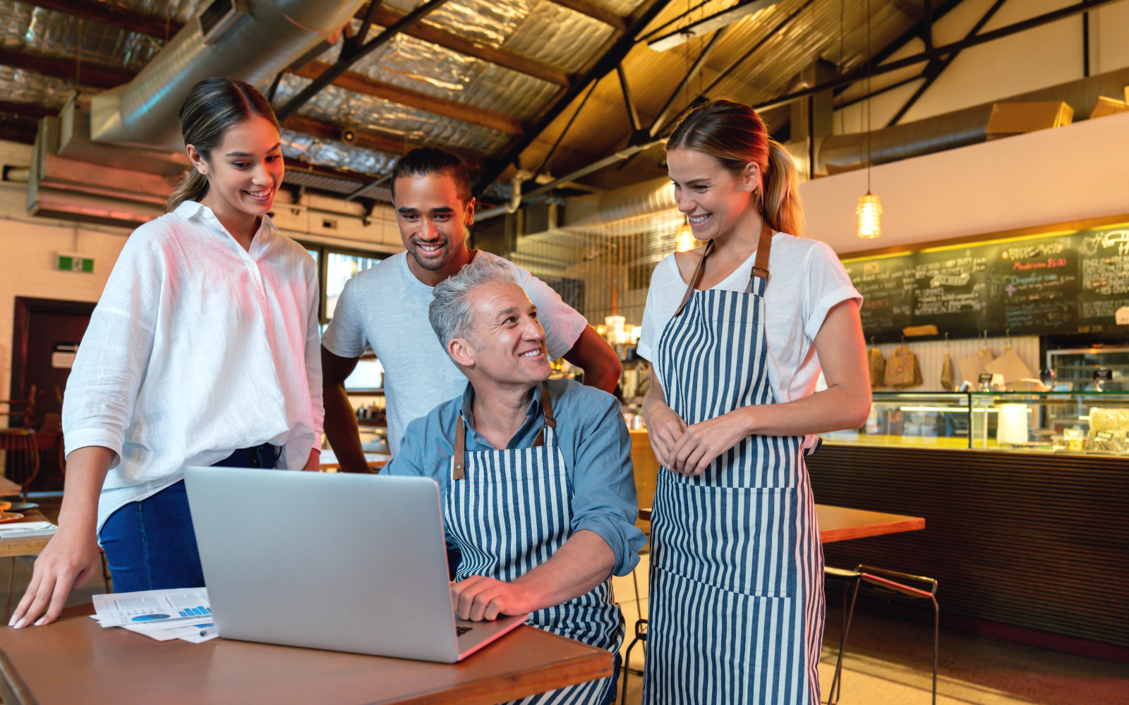 Restaurant staff around a computer smiling 