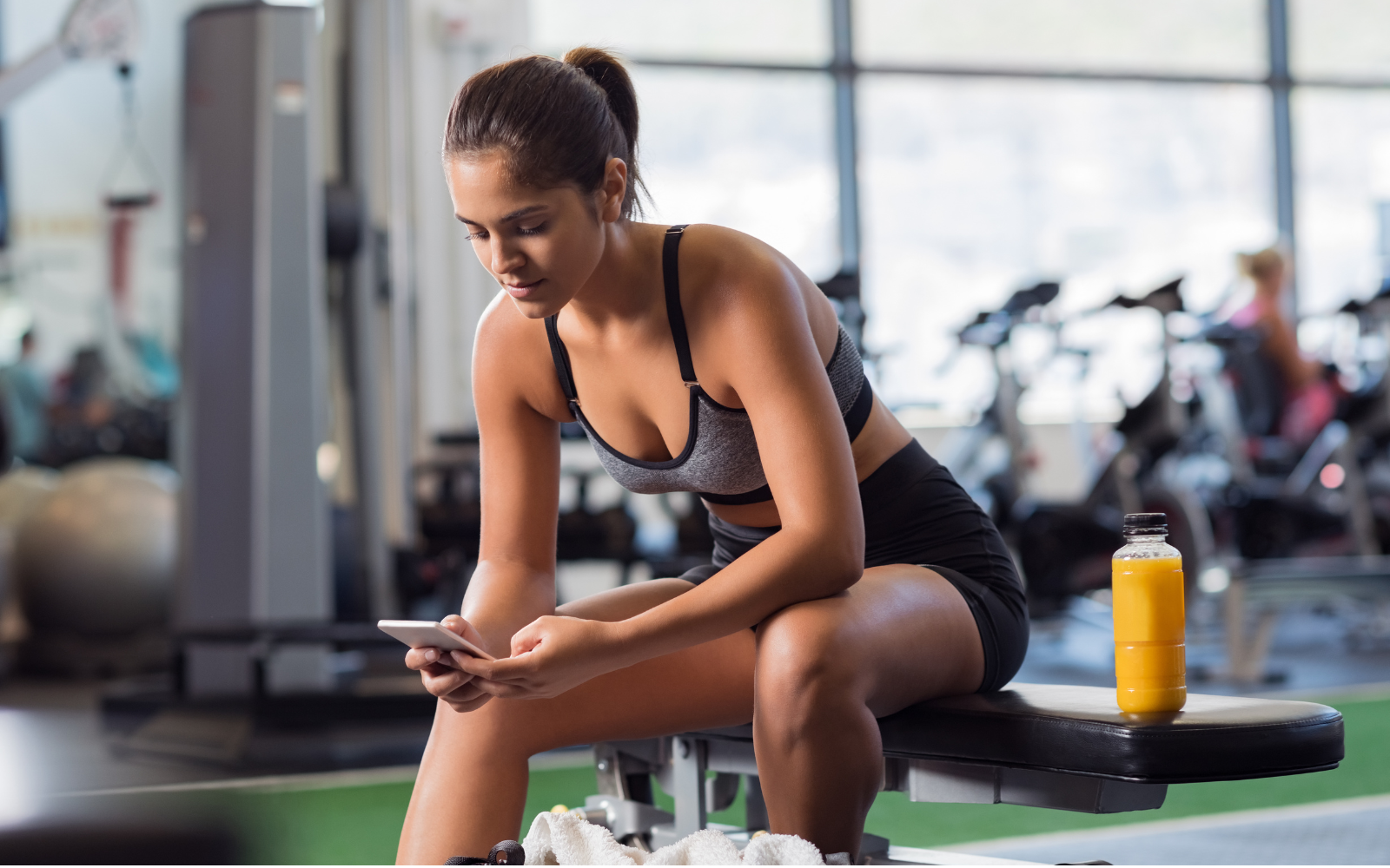 Gym goer on their mobile phone, taking a break from their workout. 